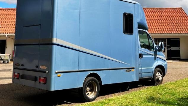 A horse box parked near a yard.